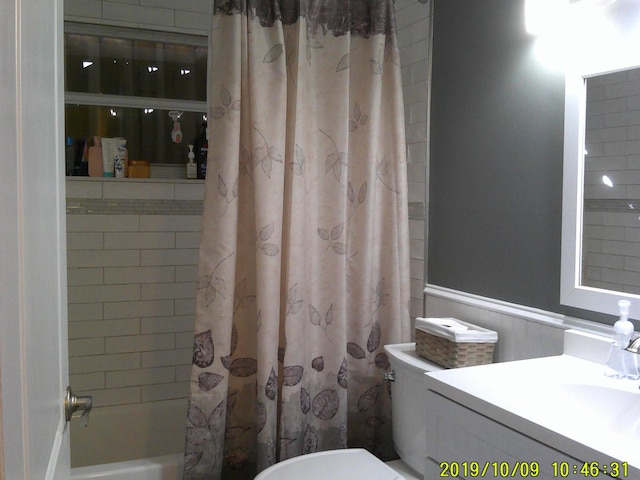 full bath with shower / bath combination with curtain, a wainscoted wall, vanity, and toilet