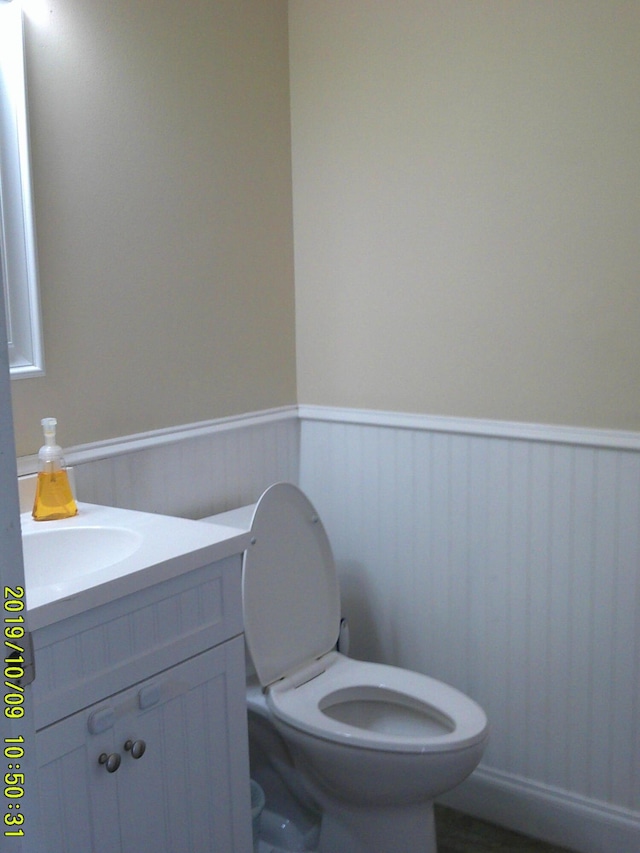 bathroom with a wainscoted wall, vanity, and toilet