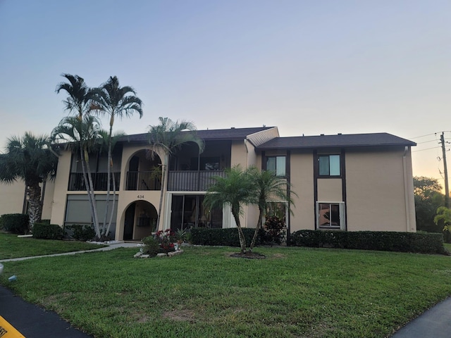 view of front facade with stucco siding and a lawn