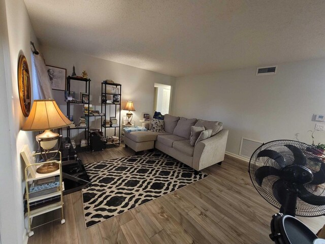 living room with wood finished floors, visible vents, and a textured ceiling