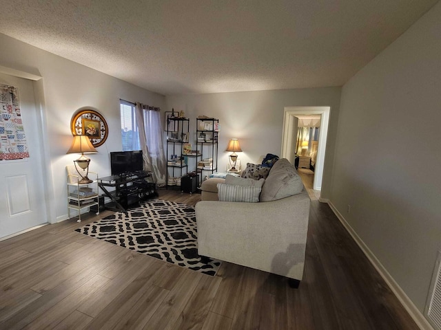 living area with baseboards, a textured ceiling, and wood finished floors