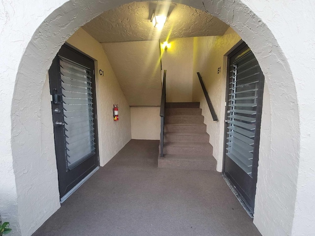 corridor featuring arched walkways and stairway