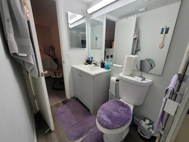 ensuite bathroom with vanity, ensuite bath, toilet, and wood finished floors