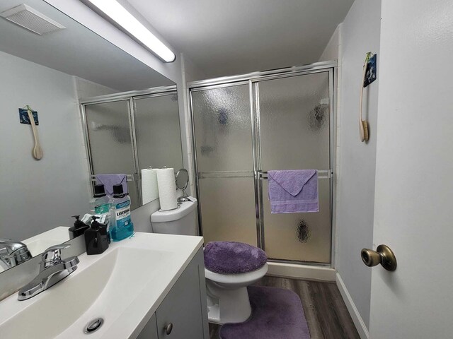 bathroom with visible vents, wood finished floors, toilet, and a stall shower