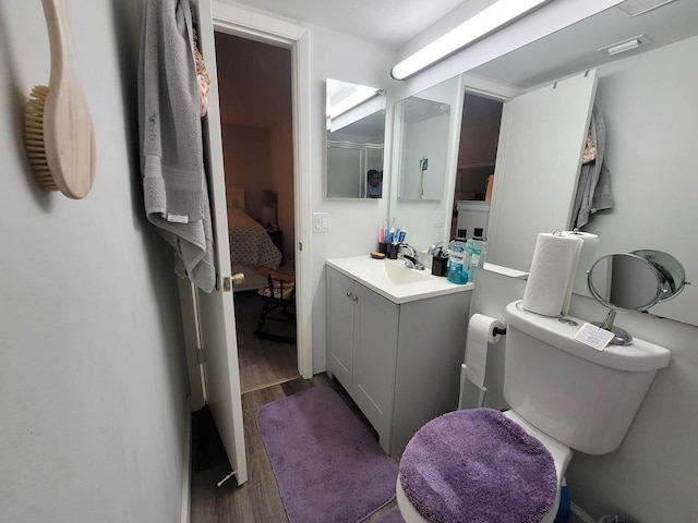 ensuite bathroom featuring toilet, vanity, ensuite bathroom, and wood finished floors