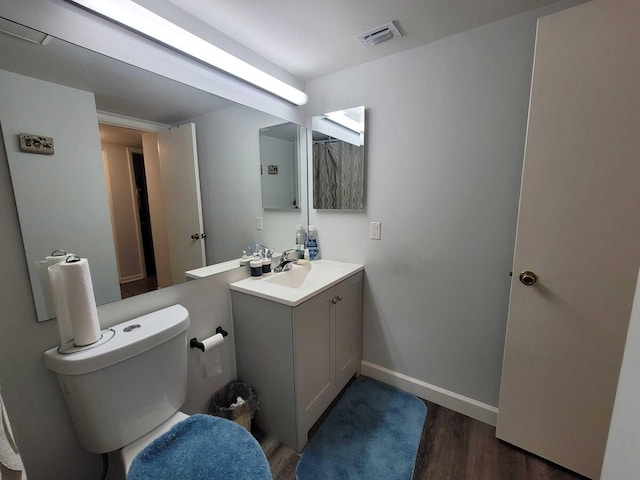 bathroom featuring vanity, wood finished floors, visible vents, baseboards, and toilet