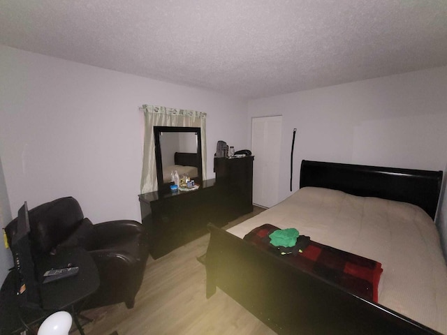 bedroom with light wood finished floors and a textured ceiling