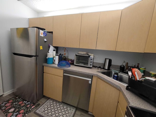 kitchen with light brown cabinets, a sink, stainless steel appliances, a toaster, and light countertops