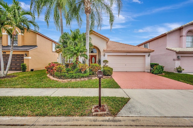 view of front of house featuring a garage, stucco siding, a tiled roof, decorative driveway, and a front yard