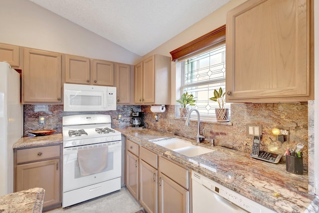 kitchen featuring lofted ceiling, white appliances, decorative backsplash, and a sink