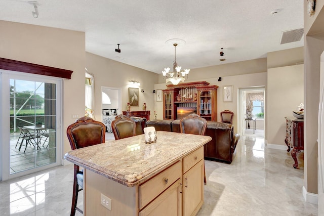 kitchen with visible vents, open floor plan, a kitchen breakfast bar, a center island, and a chandelier