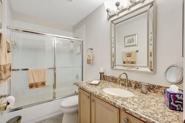 bathroom featuring vanity, toilet, and bath / shower combo with glass door