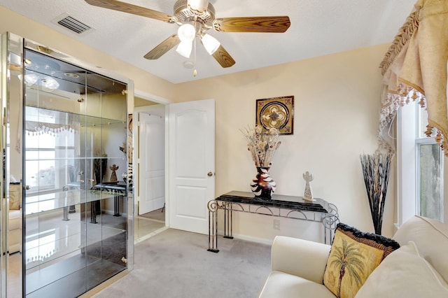 interior space featuring carpet, visible vents, ceiling fan, and a textured ceiling