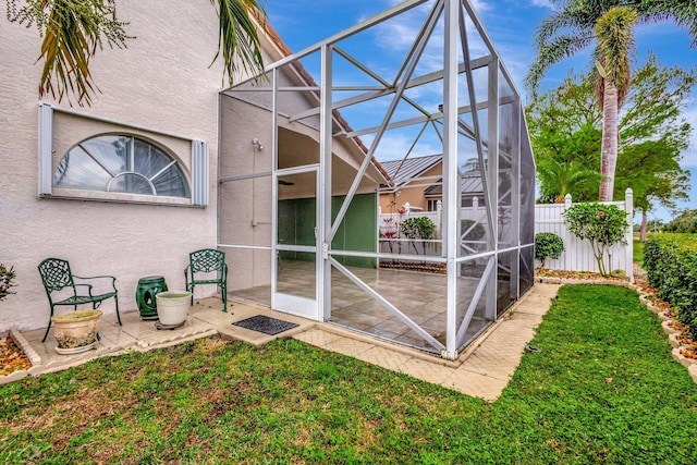 exterior space with glass enclosure, a patio area, fence, and stucco siding