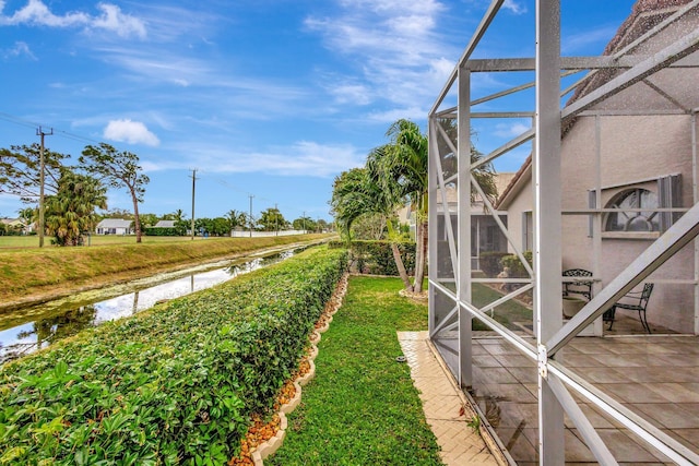 view of yard featuring a lanai, a patio area, and a water view