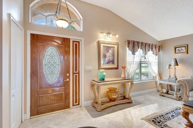 foyer with vaulted ceiling, a textured ceiling, and baseboards