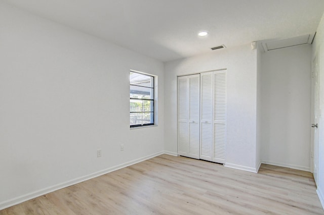 unfurnished bedroom featuring light wood-type flooring, baseboards, visible vents, and a closet