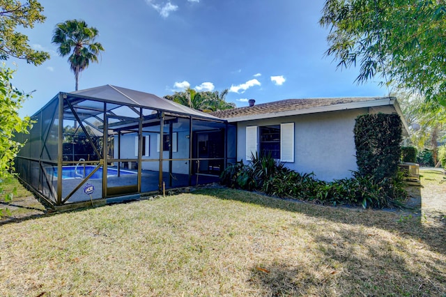 back of house featuring a fenced in pool, glass enclosure, a yard, and stucco siding