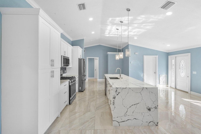 kitchen with visible vents, lofted ceiling, appliances with stainless steel finishes, a large island with sink, and a sink