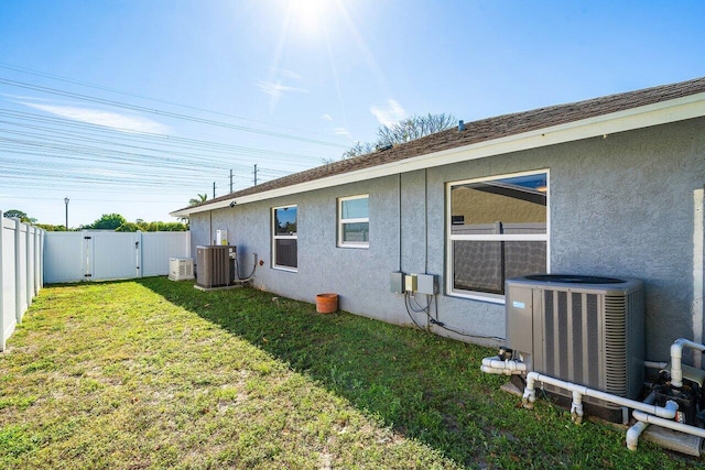 back of property featuring central air condition unit, a lawn, and stucco siding