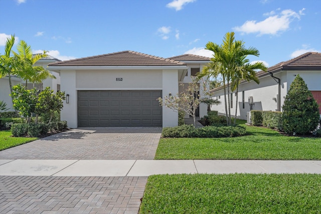 view of front of home with a garage, stucco siding, a tile roof, decorative driveway, and a front yard