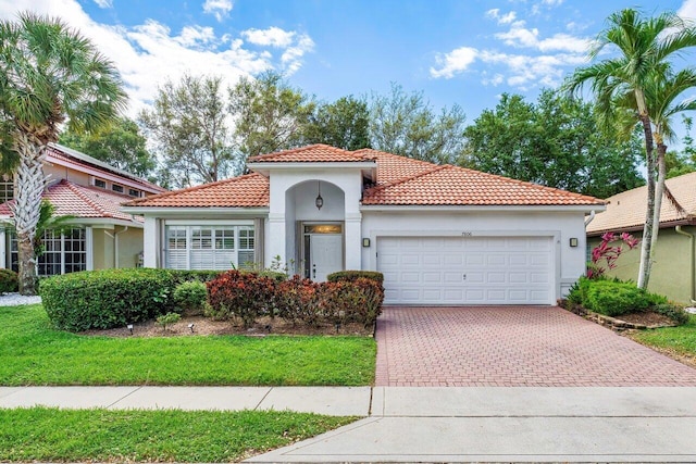 mediterranean / spanish home featuring a garage, decorative driveway, a tile roof, and stucco siding