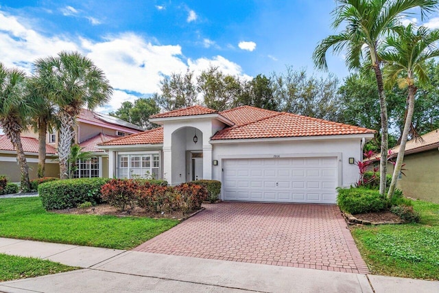 mediterranean / spanish home featuring a tiled roof, decorative driveway, a garage, and stucco siding