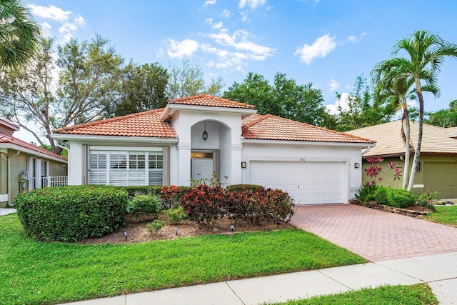 mediterranean / spanish-style house with stucco siding, a front lawn, a tile roof, decorative driveway, and a garage