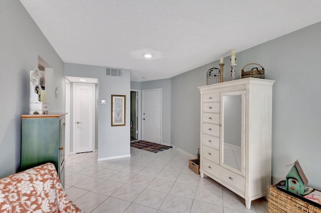 bedroom with visible vents, a textured ceiling, baseboards, and light tile patterned flooring