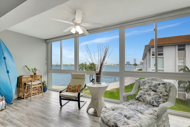 sunroom / solarium with ceiling fan, a water view, and a wealth of natural light