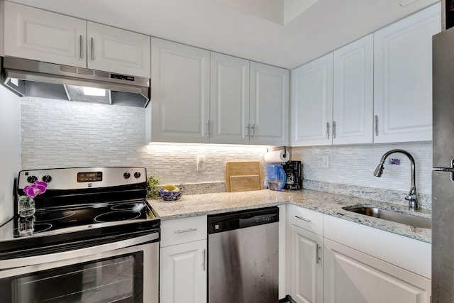 kitchen with under cabinet range hood, appliances with stainless steel finishes, decorative backsplash, and a sink