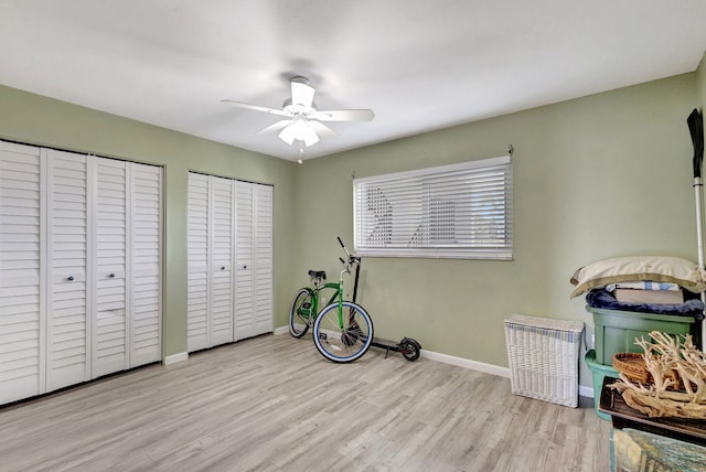 bedroom with multiple closets, a ceiling fan, baseboards, and wood finished floors