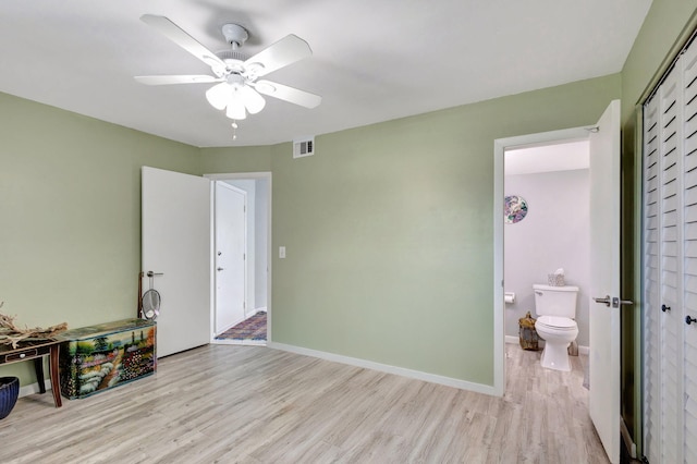 interior space with visible vents, baseboards, ensuite bath, ceiling fan, and wood finished floors