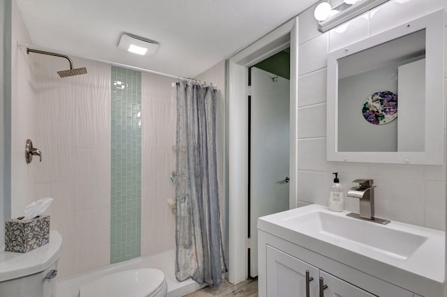 full bath with wood finished floors, tiled shower, vanity, and toilet