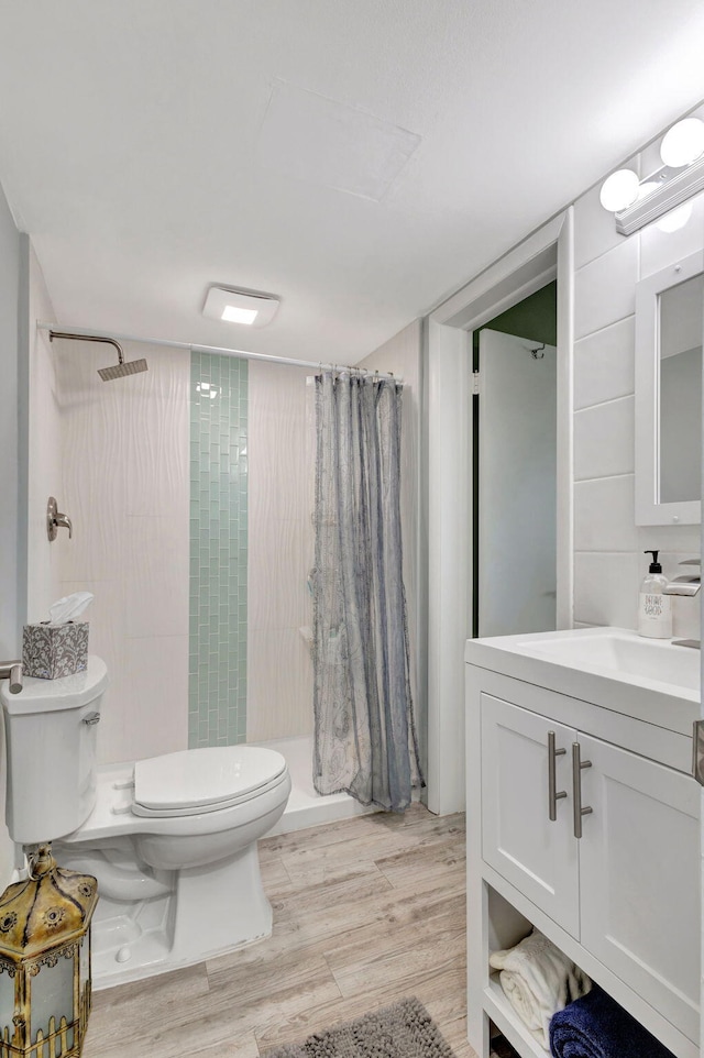 full bath featuring vanity, a shower stall, toilet, and wood finished floors