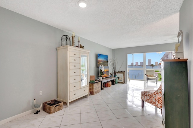 interior space with a textured ceiling, light tile patterned floors, and baseboards