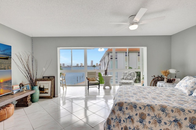 bedroom with a textured ceiling, a ceiling fan, a city view, and tile patterned floors