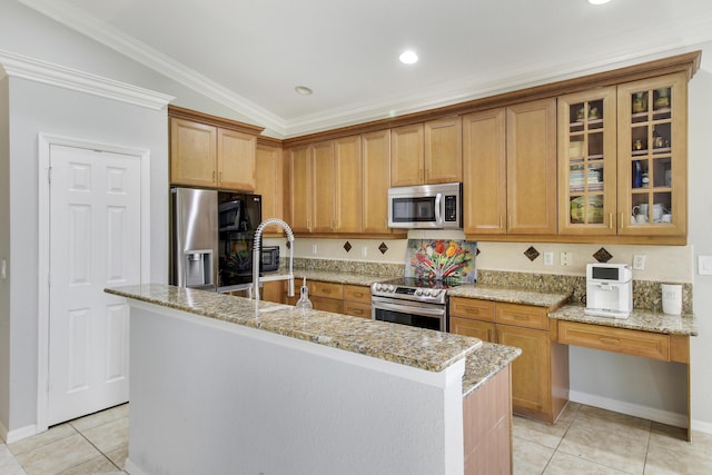 kitchen featuring light tile patterned floors, appliances with stainless steel finishes, an island with sink, and light stone countertops