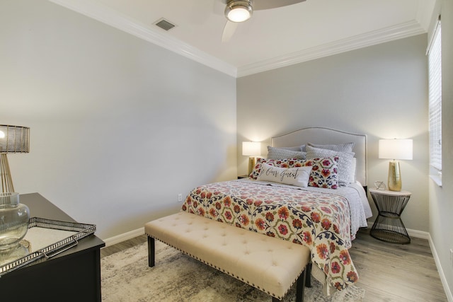 bedroom featuring visible vents, crown molding, baseboards, and wood finished floors