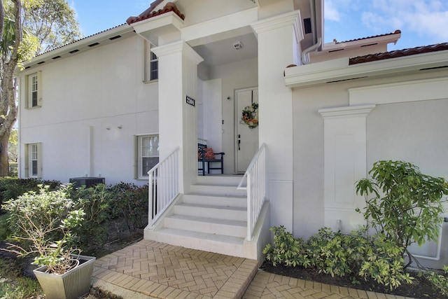 view of exterior entry with a tiled roof and stucco siding