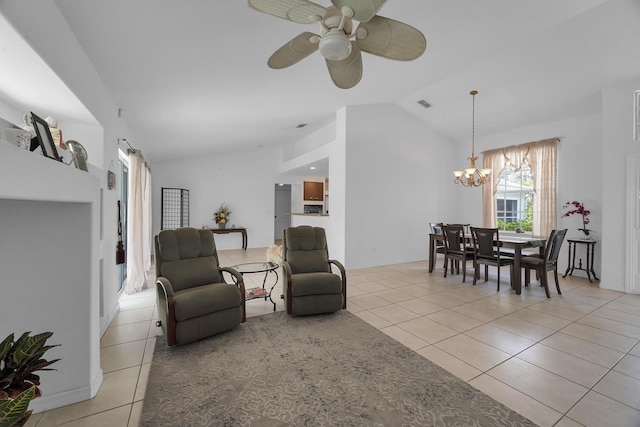 living area with ceiling fan with notable chandelier, visible vents, vaulted ceiling, and light tile patterned floors