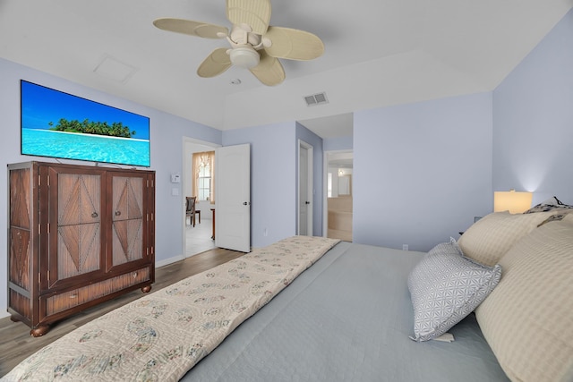 bedroom with a ceiling fan, visible vents, ensuite bathroom, and wood finished floors