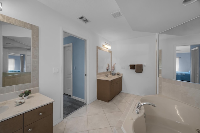 full bath with two vanities, a garden tub, visible vents, and tile patterned floors