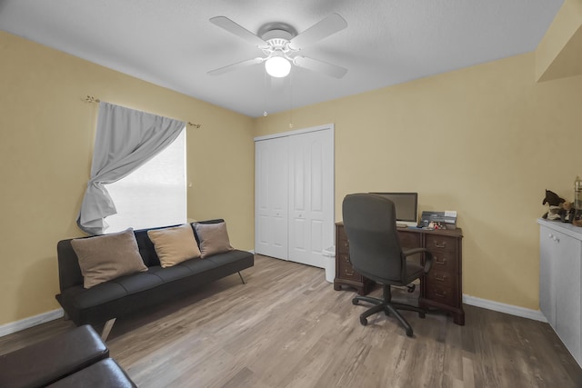 home office with a ceiling fan, baseboards, and wood finished floors