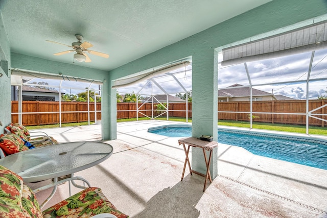 view of pool featuring a fenced in pool, a patio, glass enclosure, a fenced backyard, and ceiling fan