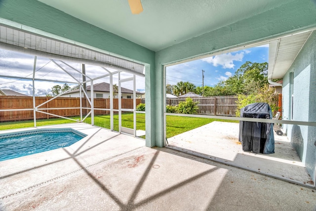 view of pool with a patio, glass enclosure, a fenced backyard, a lawn, and a fenced in pool