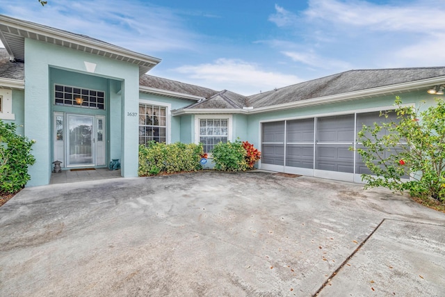 exterior space featuring a garage, concrete driveway, and stucco siding