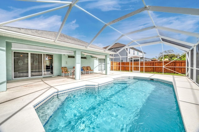 view of pool with glass enclosure, fence, a fenced in pool, and a patio