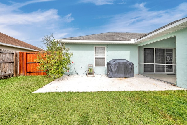 rear view of property with a yard, a patio area, fence, and stucco siding