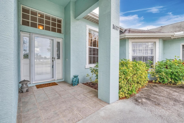 doorway to property featuring a shingled roof and stucco siding